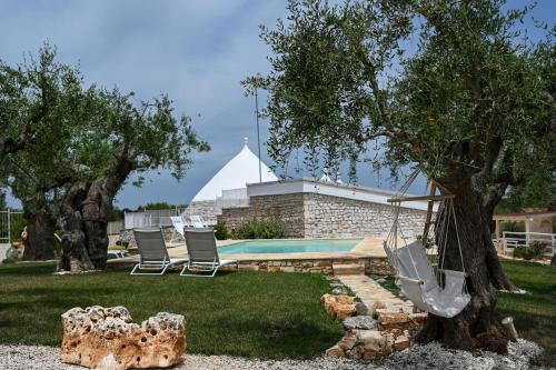 a pool with chairs and a tree and a tent at Trulli Lisanna - Exclusive Trulli With Private Pool in Antonelli