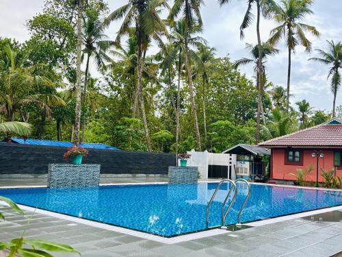 a swimming pool in front of a house with palm trees at LEISURE VALLEY BEACH RESORT in Varkala