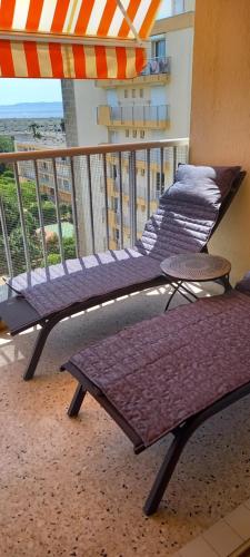 - un balcon avec 2 lits et un parasol dans l'établissement Studio vue mer Lavandou, au Lavandou