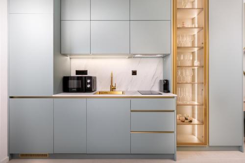 a kitchen with white cabinets and a microwave at Mint & Gold Luxury Suite in Malinska