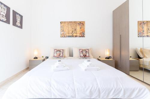 a large white bed in a white room with two lamps at I Mori Cà in Modica