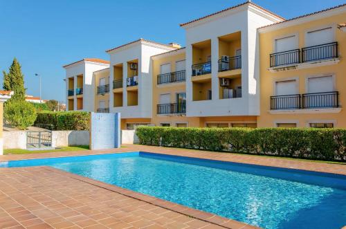 a villa with a swimming pool in front of a building at Apt MC - with pool in Alcantarilha
