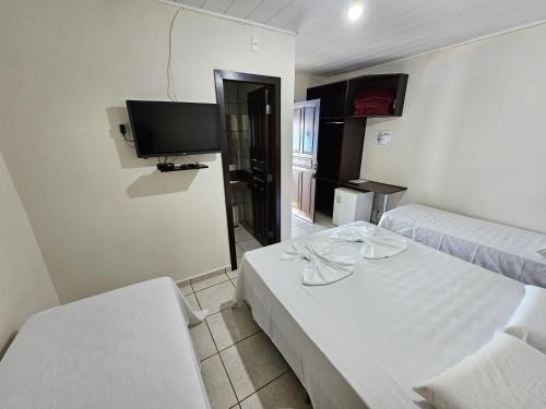 une chambre avec deux lits et une télévision à écran plat dans l'établissement Pousada Bom Jardim, à Nobres