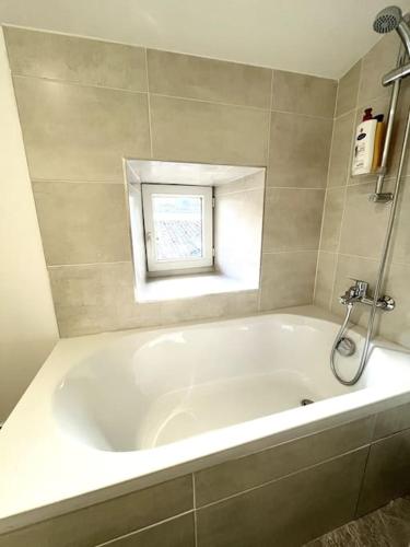 La salle de bains est pourvue d'une baignoire blanche et d'une fenêtre. dans l'établissement Le Pré Vert - Tournon, à Tournon-sur-Rhône