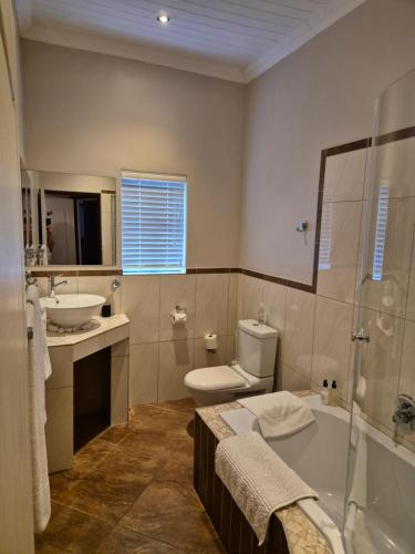 a bathroom with a tub and a sink and a toilet at On The Square Accommodation in Riebeek-Kasteel