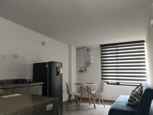 Il comprend une cuisine équipée d'un réfrigérateur et d'une table avec des chaises. dans l'établissement Apartahotel Retiro79, à Bogotá