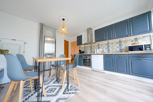 une cuisine avec des armoires bleues et une table et des chaises dans l'établissement Appartement 4 chambres - CAEN, à Caen