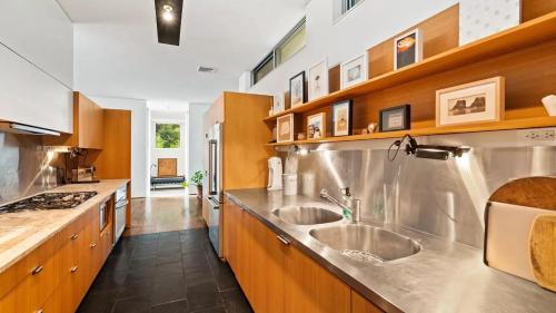 a large kitchen with two sinks and wooden cabinets at Villa Spectrum Luxury Villa with Pool & Outdoor Shower in East Hampton in Springs