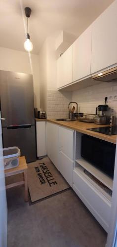 une cuisine avec des armoires blanches et un réfrigérateur noir dans l'établissement Studio Calme à 3min des plages à pied, à Marseille