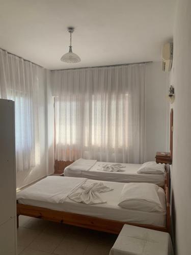 two twin beds in a room with a window at Kristal pansiyon in Ortaca