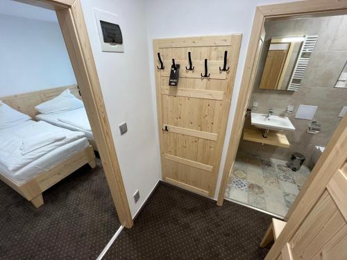 łazienka z umywalką, łóżkiem i lustrem w obiekcie Hotel Rankl w mieście Horská Kvilda