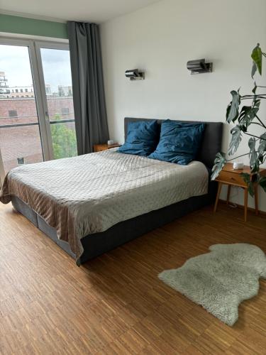 a bedroom with a bed with blue pillows and a window at Penthouse-Wohnung mit Flussblick in Oldenburg