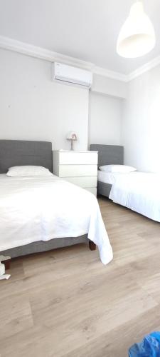 a white bedroom with two beds and a wooden floor at Zumra's White Houses in Trabzon