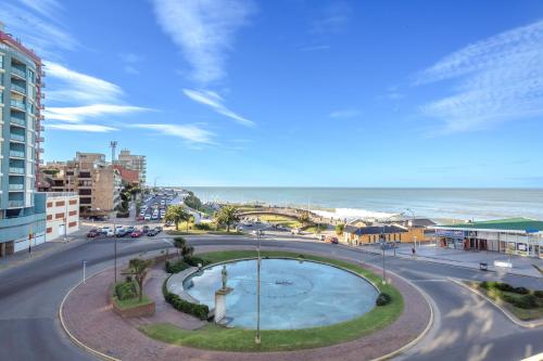 a view of a street with a fountain and the ocean at Hotel Iruña in Mar del Plata