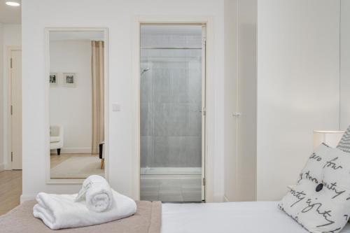 a bedroom with a white bed with a mirror at Studios Funchal in Funchal