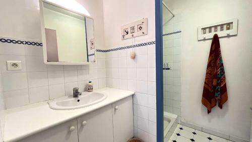 une salle de bain blanche avec un lavabo et un miroir dans l'établissement Jolie villa de plain pied avec agréable jardin, à Saint-Clément-des-Baleines