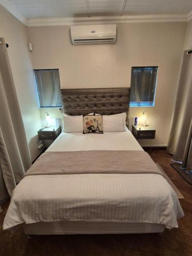 a bedroom with a large white bed with two tables at On The Square Accommodation in Riebeek-Kasteel