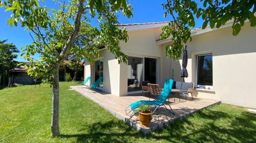 d'une terrasse avec des chaises et un arbre dans une cour. dans l'établissement Alice’s house, Maison & Grange à 10km de l’Océan, à Naujac-sur-Mer