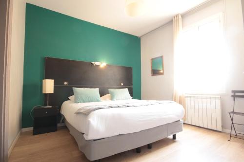 a bedroom with a large bed with a blue wall at Hôtel Des Arts, Artisanal et Indépendant in Montpellier