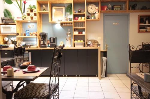 a kitchen with a table and chairs and a clock at Hôtel Des Arts, Artisanal et Indépendant in Montpellier