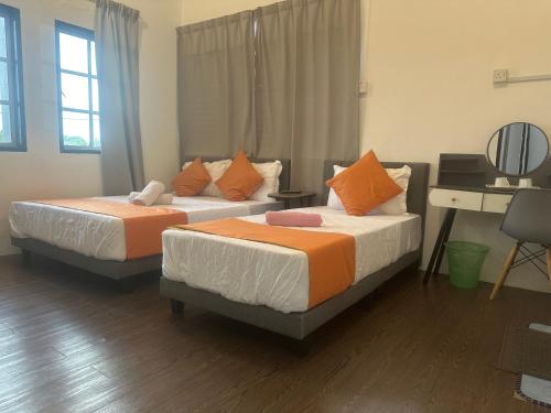 two beds in a room with a desk at Jenny Homestay in Teluk Intan
