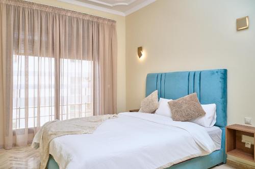 a bedroom with a bed with a blue headboard and a window at YourPlace Rabat Agdal 1 - Cozy Residence in Rabat