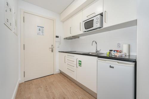 a white kitchen with a sink and a microwave at Studios Funchal in Funchal