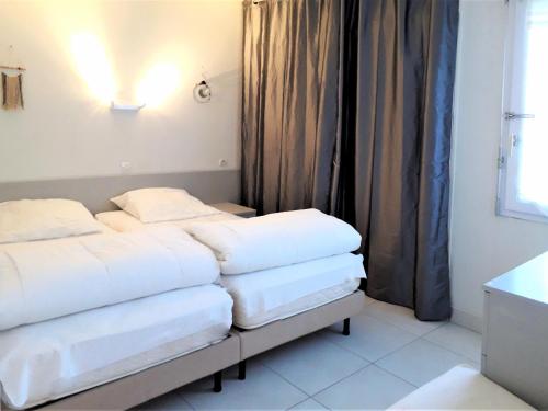 zwei Betten in einem kleinen Zimmer mit Fenster in der Unterkunft Appart du golf in Saint-Jean-de-Monts