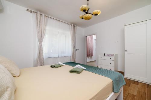 a bedroom with a large white bed and a window at Holliday house Smokvica in Jadranovo