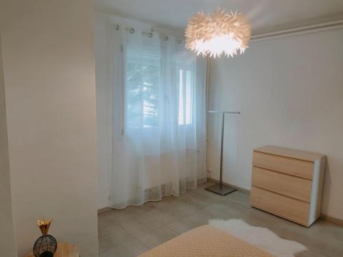 Cette chambre blanche dispose d'une commode et d'un lustre. dans l'établissement Villa indépendante avec piscine au rdc, à Nyons