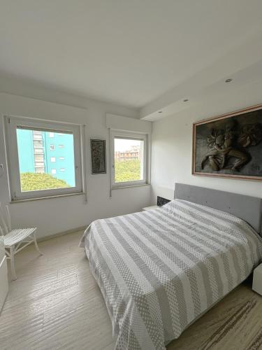 a white bedroom with a large bed and two windows at Charm in centre, sunset, movida! in Milano Marittima