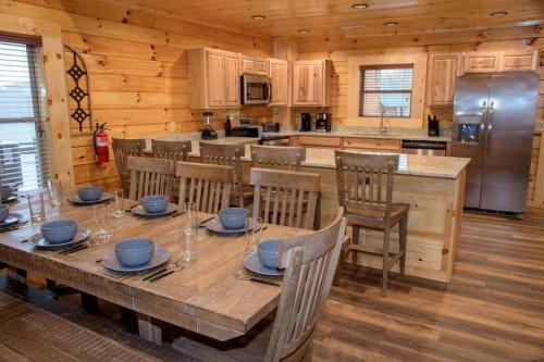a kitchen with a wooden table with chairs and a refrigerator at Spacious 2800 sq ft-Cozy Wood Cabin-NEW BUILD in Pigeon Forge