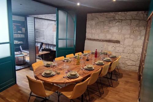 une grande table en bois entourée de chaises dans l'établissement maison de village, à Laplume