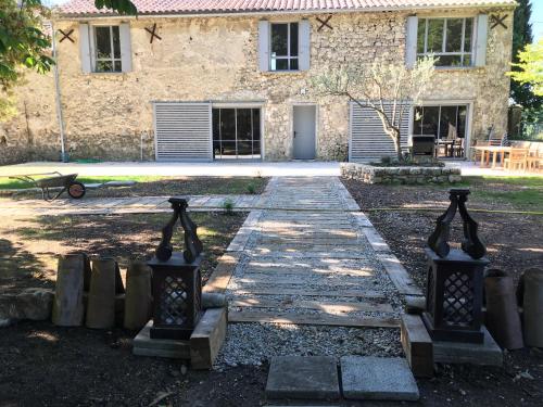 un bâtiment en pierre avec un chemin devant lui dans l'établissement Domaine de Charme - Drôme Provençale - Grignan, à Roussas
