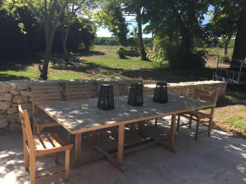 une table en bois avec deux chaises et un mur en pierre dans l'établissement Domaine de Charme - Drôme Provençale - Grignan, à Roussas