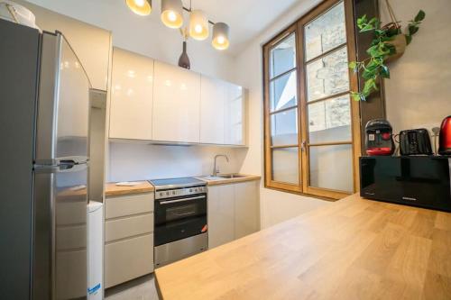 une cuisine avec des armoires blanches et un réfrigérateur noir dans l'établissement Le Pampille, Grand T2, Climatisé, Centre ville, à Montpellier