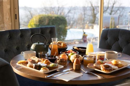 a table with breakfast foods and drinks on it at L'Orée du Bois - Hôtel & Spa in Montagudet