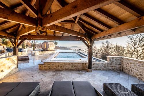 an outdoor patio with a pool and a wooden roof at L'Orée du Bois - Hôtel & Spa in Montagudet