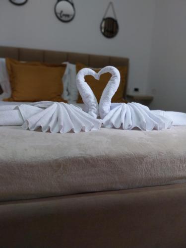two white swans are sitting on a bed at Apartment Ross in Vlorë