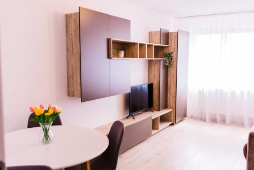 a living room with a table and a tv at Riverside White Apartment in Satu Mare