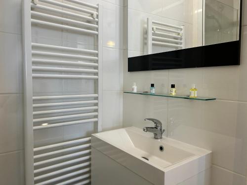 une salle de bain blanche avec un lavabo et un miroir dans l'établissement 103 - Appartement vue mer pour 4 personnes, à Fréhel