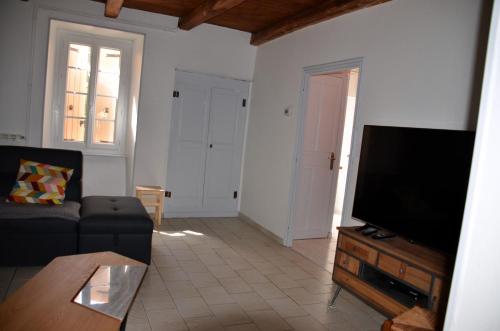 un salon avec un canapé et une télévision à écran plat dans l'établissement Gîte Chez Elie, à Comprégnac