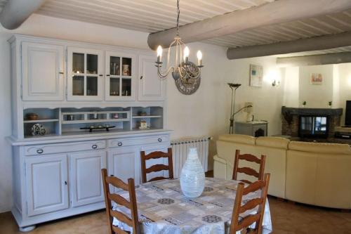 a kitchen with white cabinets and a table with chairs at La Villa St Antoine in LʼIsle-sur-la-Sorgue