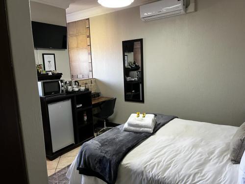 a bedroom with a bed and a kitchen with a microwave at Klyne Jiweel Guesthouse in Pretoria