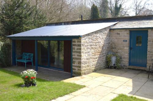 a pavilion with a blue door in a yard at The Old Wash House Chatsworth Estate in Baslow