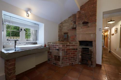 a bathroom with a stone fireplace and a sink at The Old Wash HouseChatsworth Estate in Baslow
