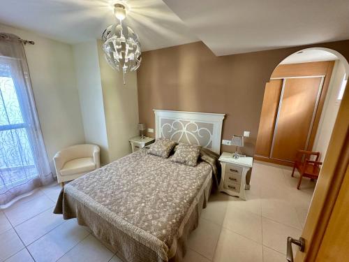 a bedroom with a bed and a chandelier at Impresionante Ático en Torre del Mar frente al Mar in Torre del Mar