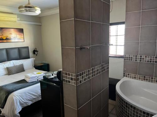 a bathroom with a bed and a bath tub next to a bedroom at Klyne Jiweel Guesthouse in Pretoria