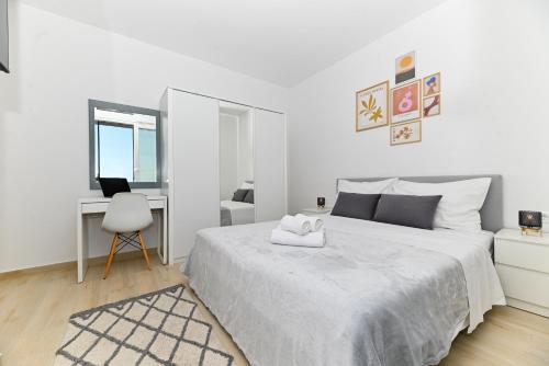 a white bedroom with a large bed and a desk at Luxury Apartment Skyline in Split