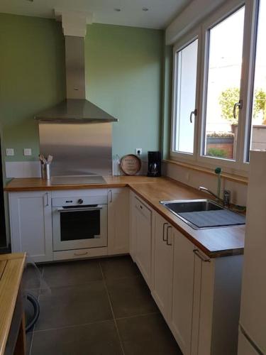 une cuisine avec un évier et une cuisinière four supérieur dans l'établissement la Brise Malouine au bord de mer avec jardin, à Dunkerque